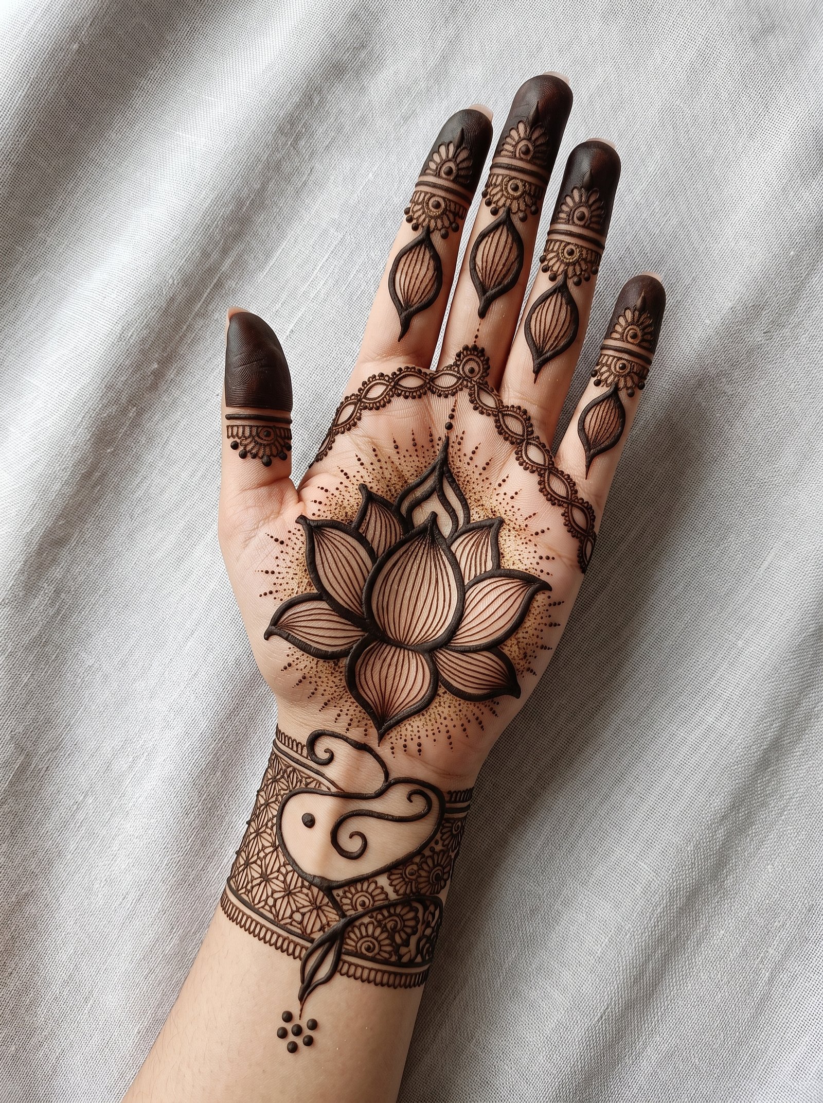 Front hand mehndi design featuring a large lotus flower, detailed finger motifs, dotted patterns, and an intricate wrist design.