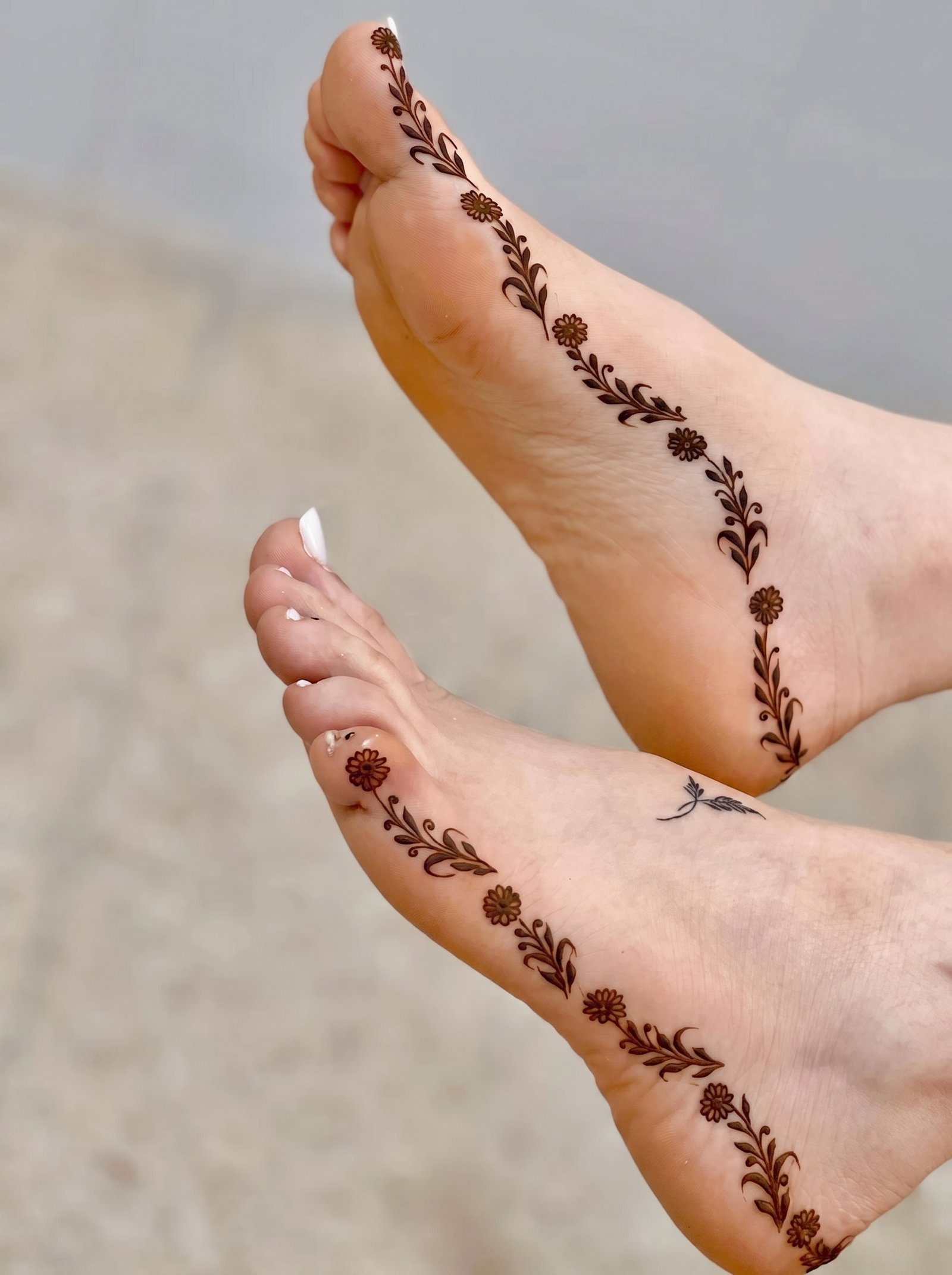 Minimal feet mehndi design featuring floral motifs and delicate leafy vines extending from the toes to the ankles.