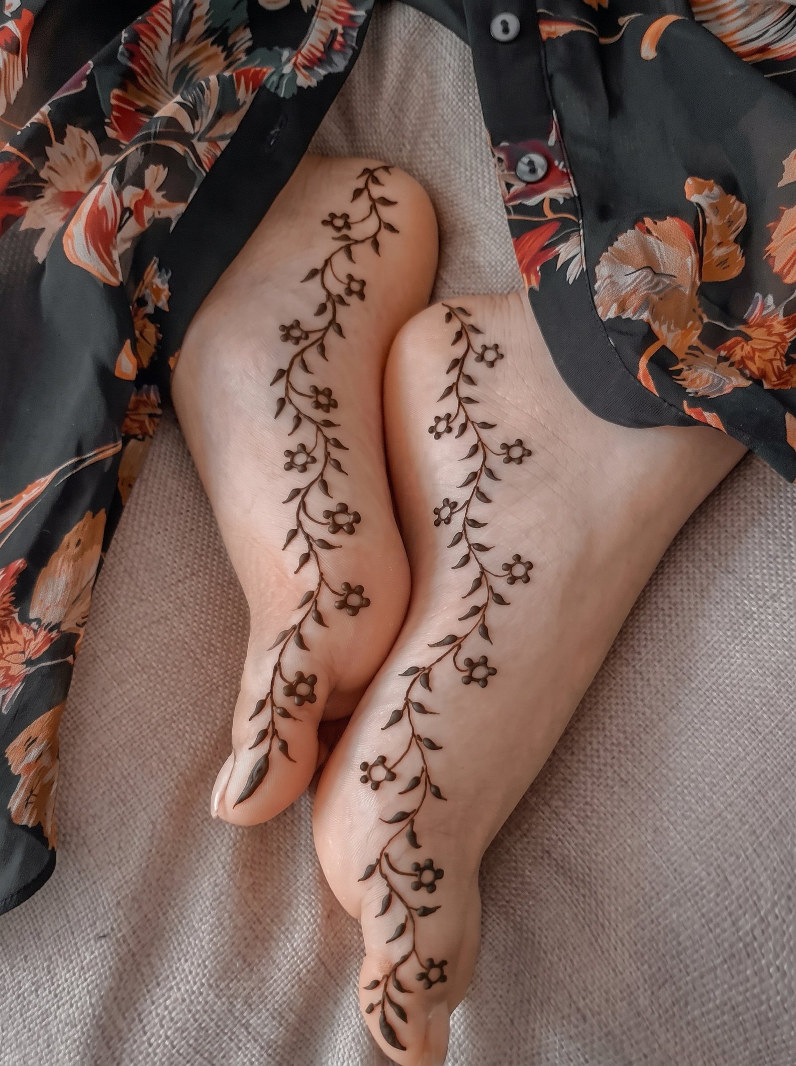 Simple feet mehndi design featuring delicate floral vines, small flowers, and leafy patterns on both feet.