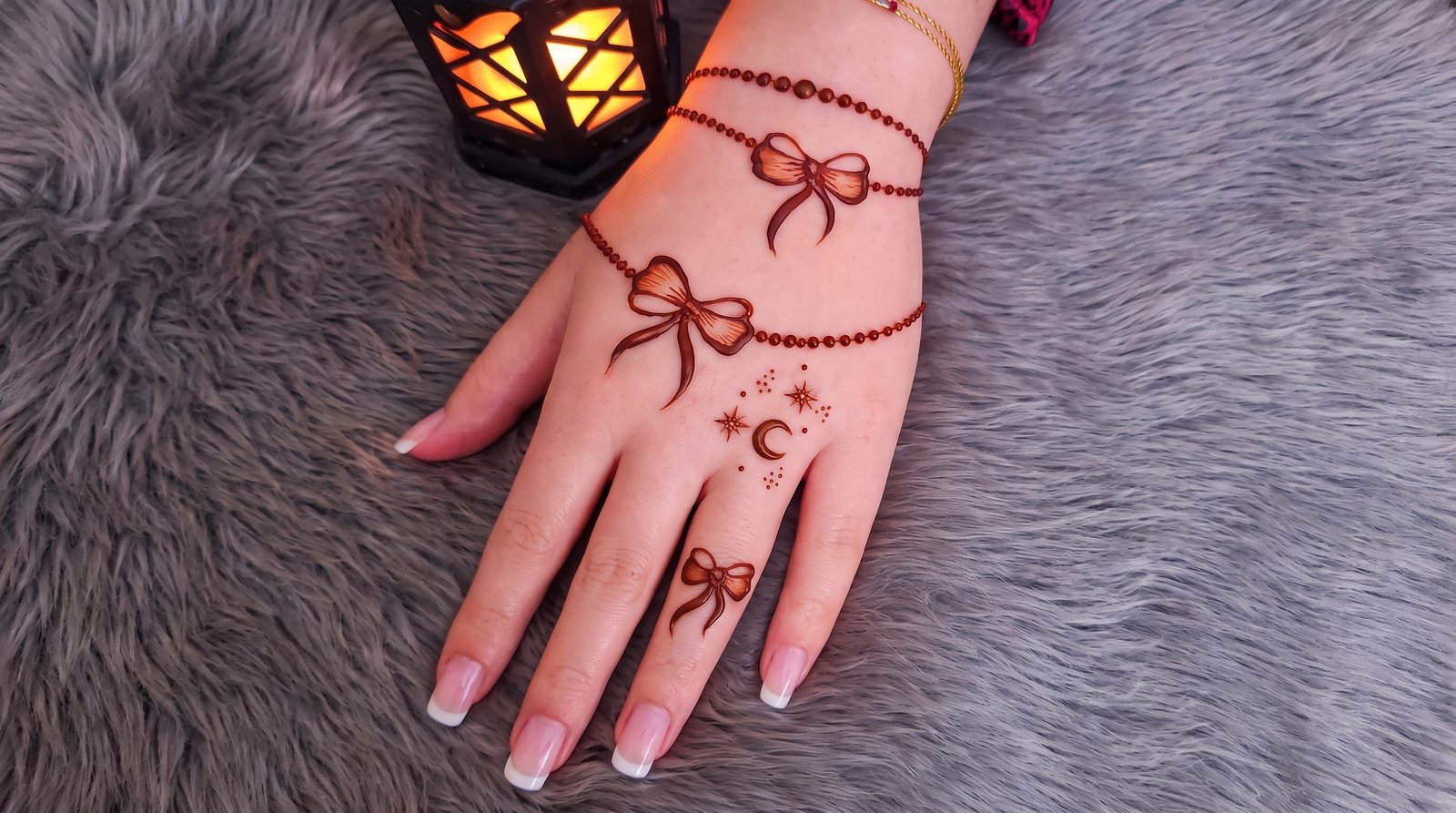 Elegant Pakistani mehndi design featuring bow motifs, dotted bracelet patterns, and crescent moon and star details on the hand.