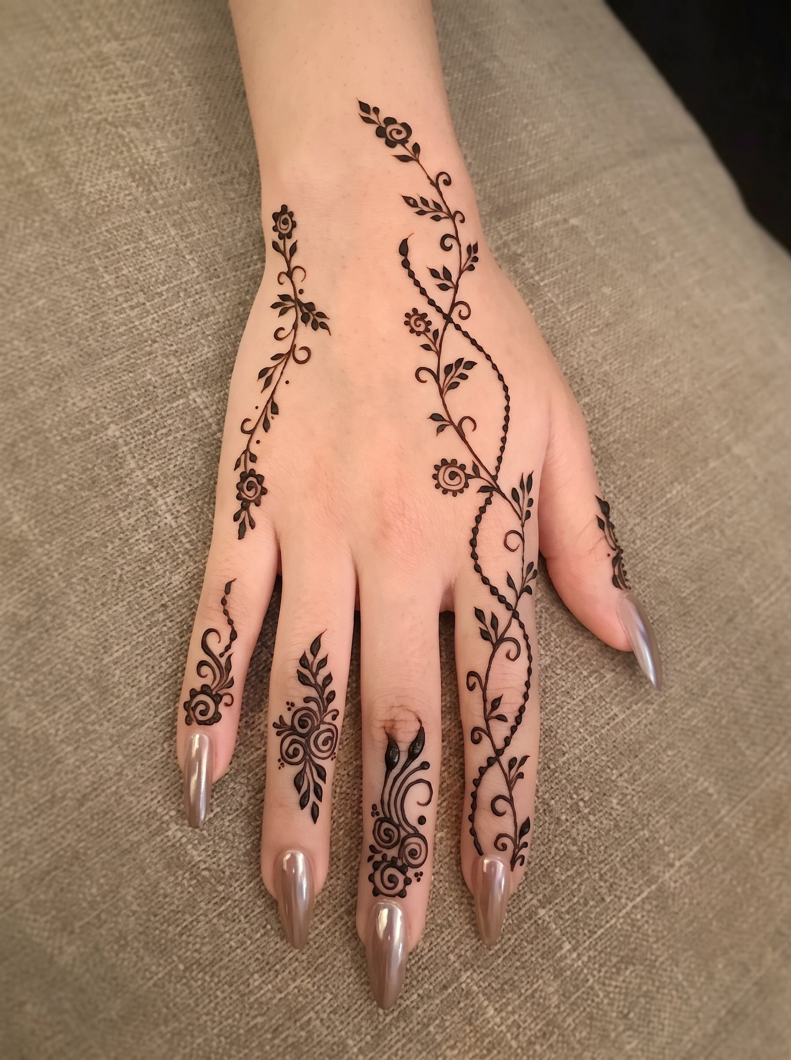 Simple floral mehndi design with leafy vines and delicate patterns on the back of the hand