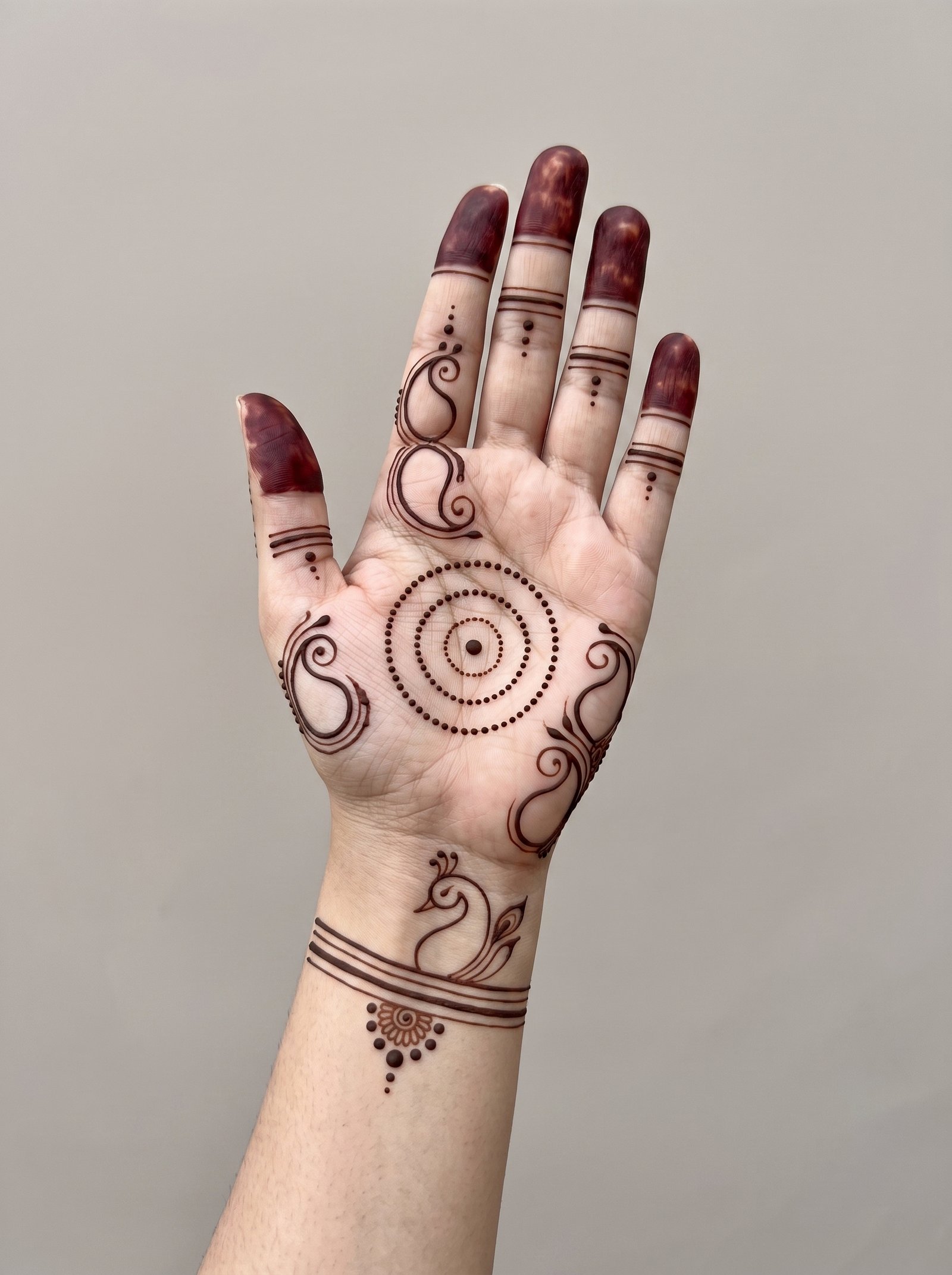 Elegant bridal mehndi design with peacock motif, circular pattern, paisley details, dotted accents, and bold fingertips.