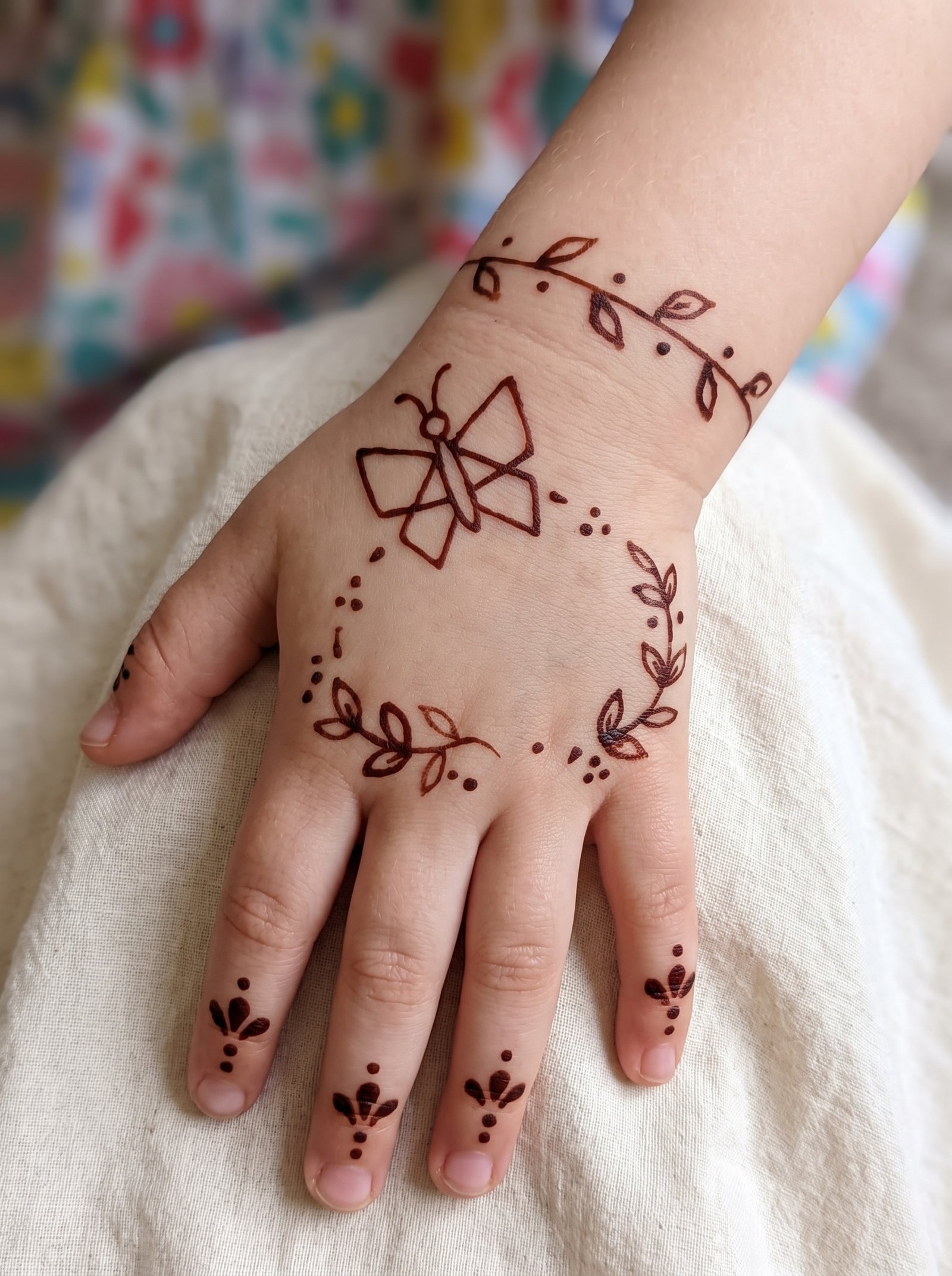 Cute kids mehndi design with a simple flower, leafy vines, dots, and finger patterns